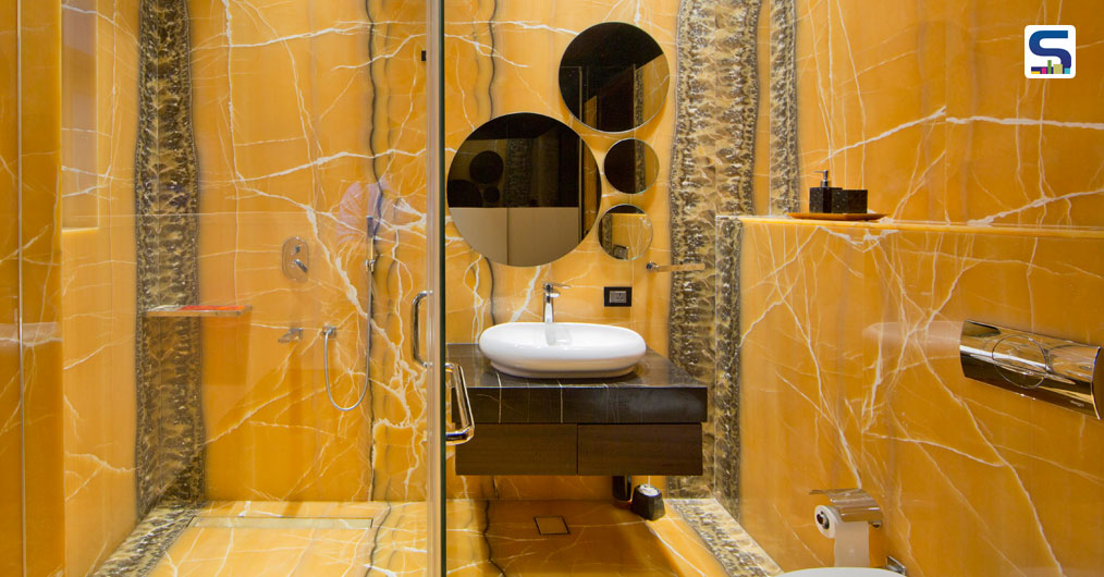 The couple, who wanted their children to get spoilt-forchoice, chose a Brazilian Quartzite (corteccia) for their son’s bathroom. This stone has an eclectic color palette with oceanic waves of grey, beige, ivory, tan and brown. The intent of wrapping this stone around on most walls in this bathroom was to make it synonymous with the depth of the ocean. Complimenting playful angles were added via lighting and shape of mirror. Blue LED light behind mirror represents water. This stone added color to this bathroom in a suave manner.